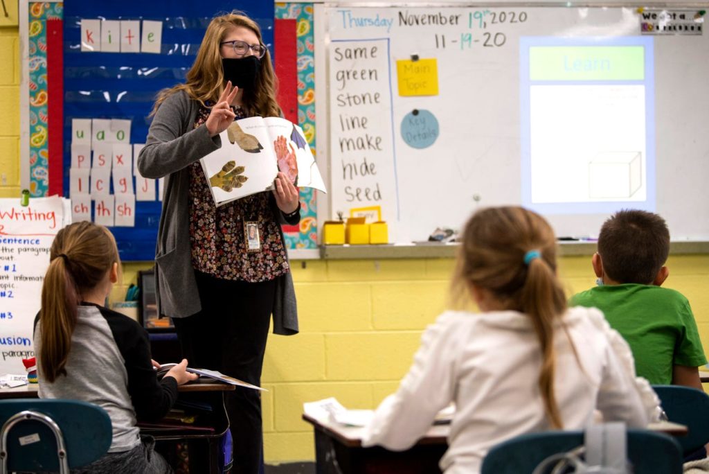 Female teacher reading to elementary students.